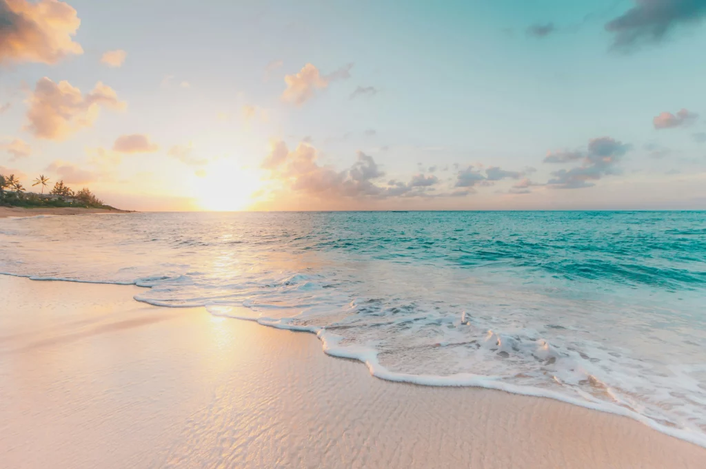 Coucher de soleil apaisant sur une plage de sable fin avec vagues douces.